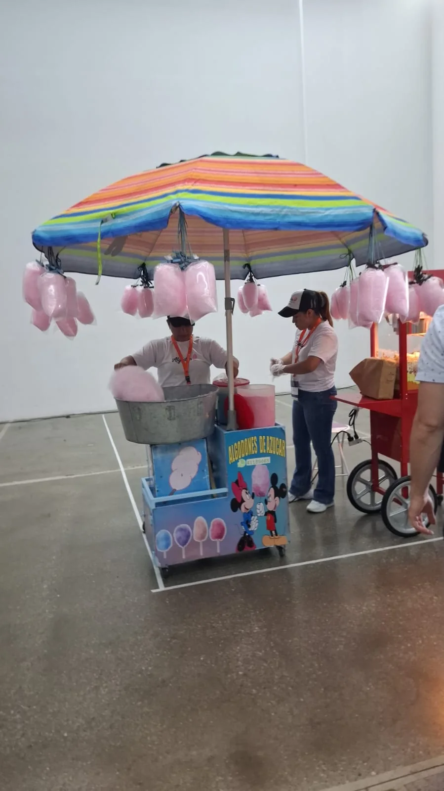 Estación de algodón de azúcar atendida por personal en un evento